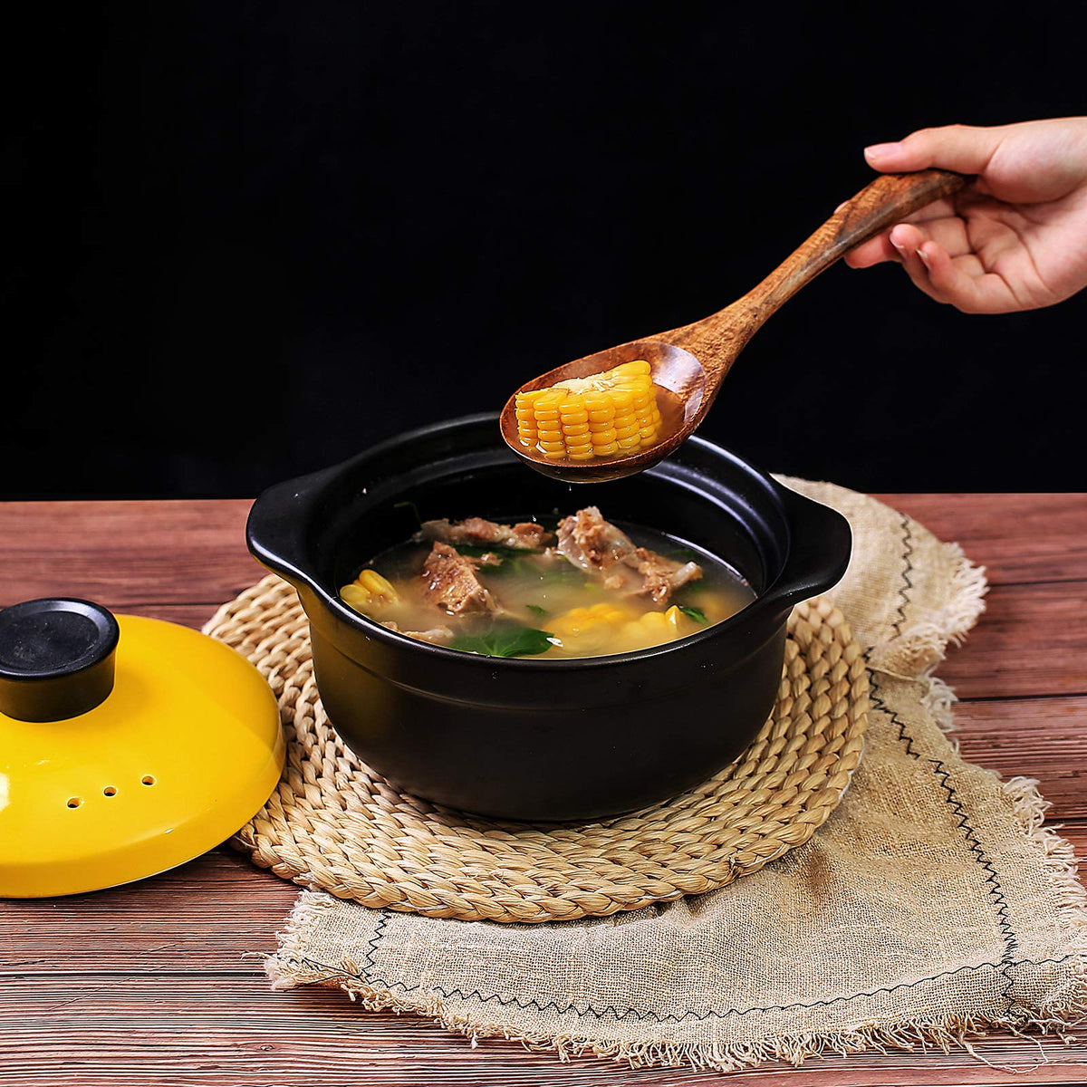 Wooden kitchen spoon serving food from a black cooking pot
